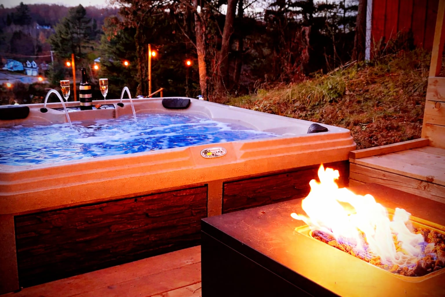 Outdoor hot tub and fire pit at The Muskoka River Chalet at dusk, overlooking the Muskoka River in Bracebridge, Ontario