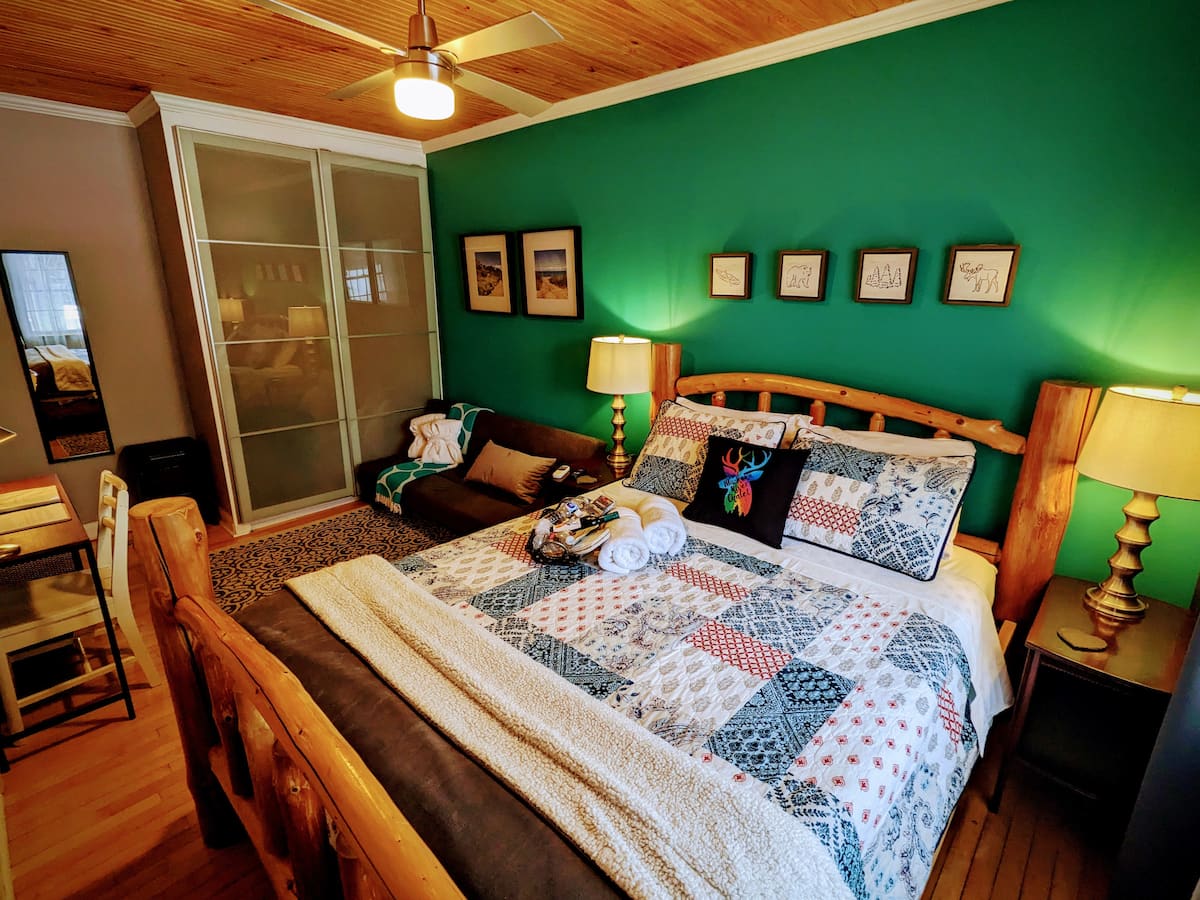 The Queen's Corgi Room at The Muskoka River Chalet with a log-frame queen bed, emerald green accent wall, and cottage-chic decor